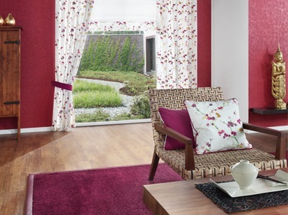 Wohnzimmer mit roten Details, Sessel mit Dekostoff Kissen und Vorhaenge